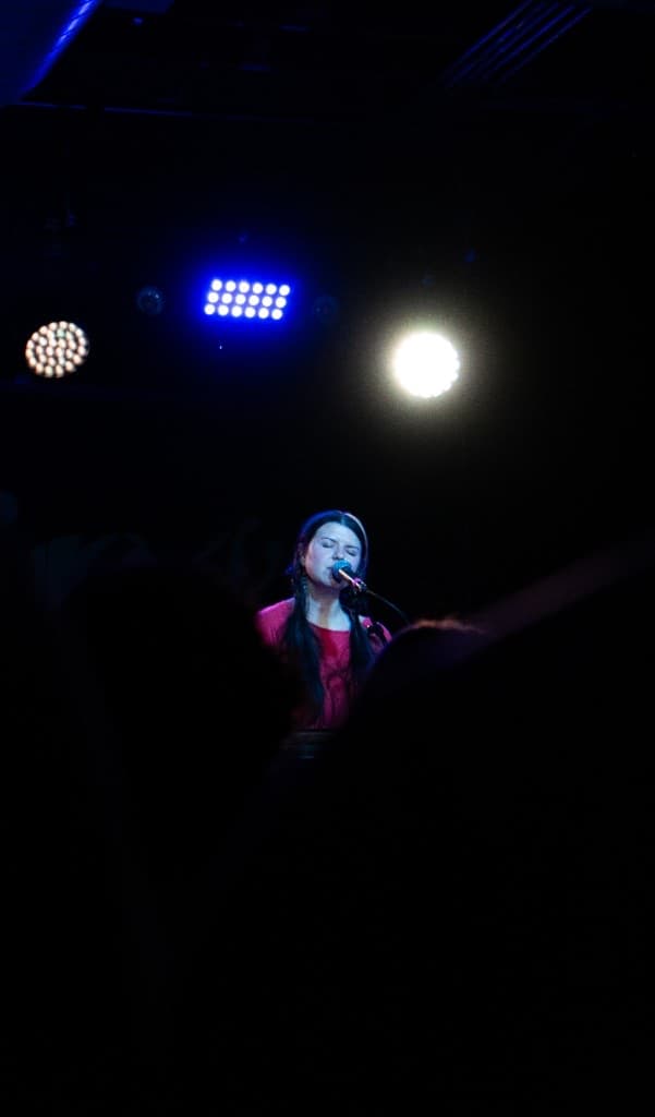 Vocalist performing under blue and white stage lights