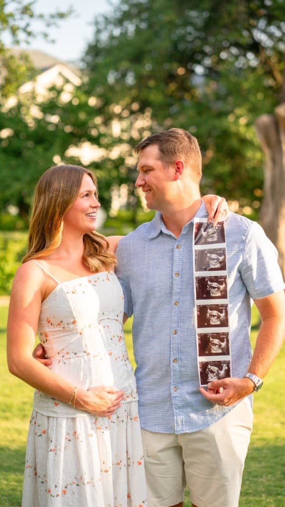 Expectant couple standing together outdoors with ultrasound photos