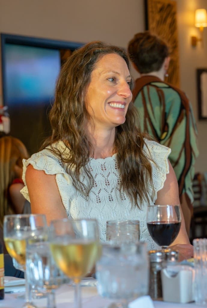 Woman smiling at a table set with wine glasses
