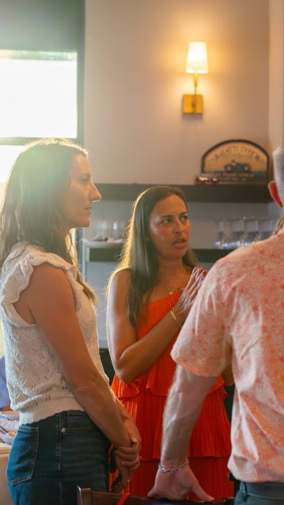 Three people in conversation at a table in warm indoor light
